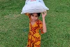 Reconnaissante, cette petite fille robuste porte le grand colis humanitaire. (csi)