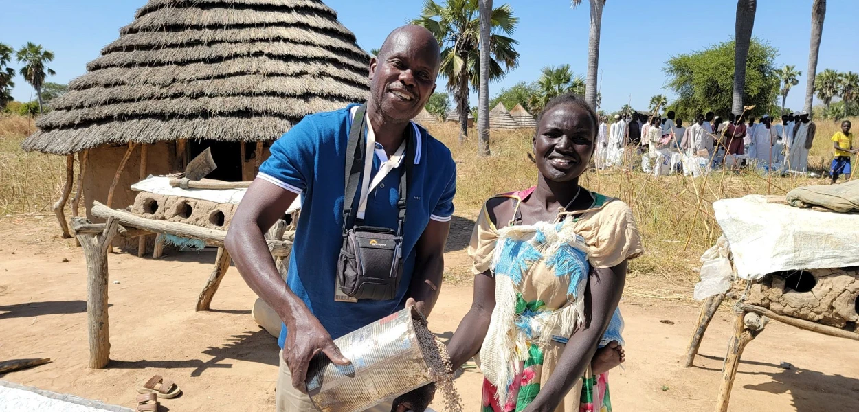 Un moment de joie : Franco Majok, responsable CSI pour le Soudan du Sud, remplit un sac de sorgho pour Ajok. csi