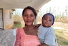 Primo piano di donna nigeriana sorridente con in braccio il suo bebé. csi